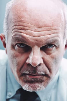 Close-up portrait of a serious mature businessman with a stern expression staring intensely at the camera, conveying authority, focus, and determination
