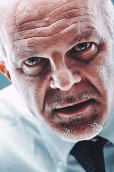 Close-up portrait of a mature businessman, displaying a skeptical expression while looking suspiciously at the camera, effectively conveying feelings of distrust and doubt