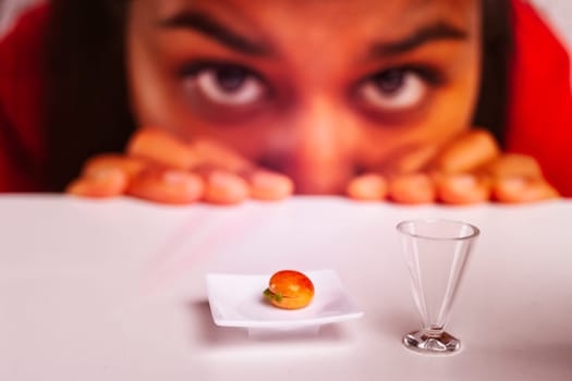 Young woman looking with surprise at a tiny portion of food served on a small plate, symbolizing the concept of diet and microscopic portions