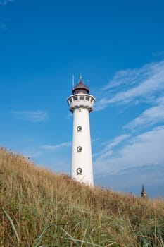 The approx. 28 m high white lighthouse J.C.J. van Speijk in Egmond aan Zee, North Holland, Netherlands, in the sand dunes with beach grass