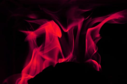 Flames from a fire in pink against a black background