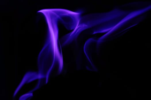 Flames from a fire in blue against a black background