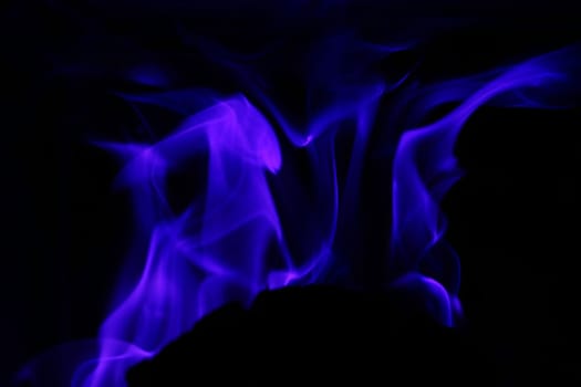 Flames from a fire in blue against a black background