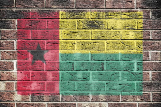 A Guinea-Bissau flag on brick wall background red yellow green star black