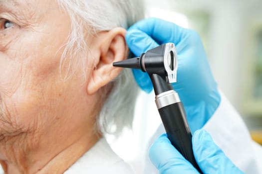 Otolaryngologist or ENT physician doctor examining senior patient ear with otoscope, hearing loss problem.