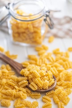 Uncooked italian pasta. Radiatori pasta in spoon on a white table.