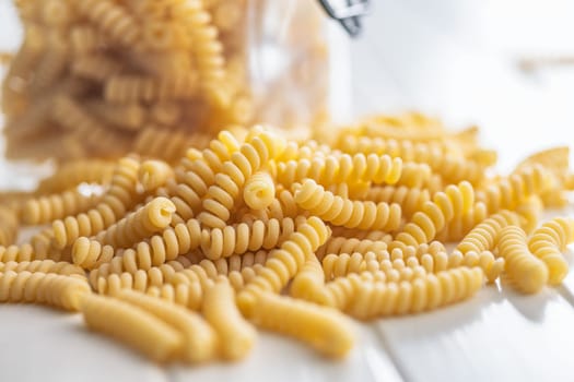 Uncooked italian pasta. Fusilli pasta on a white table.