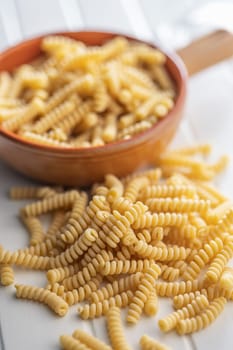 Uncooked italian pasta. Fusilli pasta on a white table.