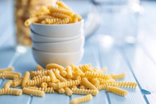 Uncooked italian pasta. Fusilli pasta on a blue table.
