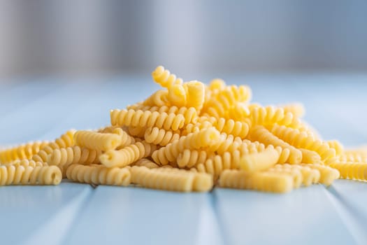 Uncooked italian pasta. Fusilli pasta on a blue table.