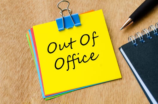 Top view of Out of Office text on yellow notepad. Holiday or vacation and away from work concept.