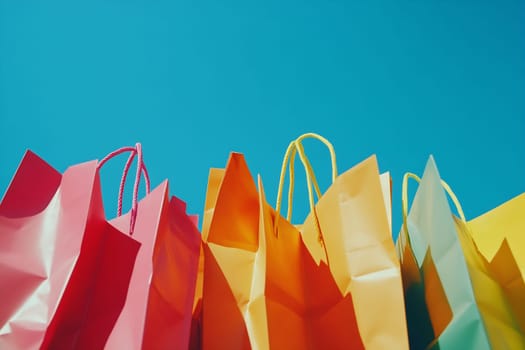 Brightly colored shopping bags are arranged against a clear blue sky, creating a cheerful and vibrant atmosphere.