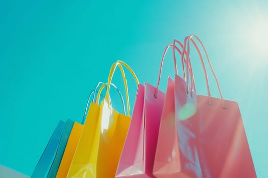 Vibrant shopping bags in yellow, pink, and blue are beautifully arranged against a clear blue sky, reflecting sunlight in a cheerful display.