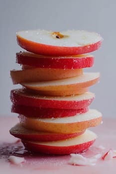 Fresh red apple slices are stacked neatly, glistening with moisture, perfect for a healthy snack or garnish.