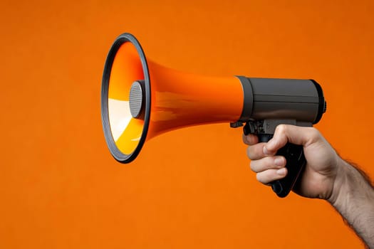 A person holds a handheld megaphone against a bright orange background, ready to communicate loudly and effectively.