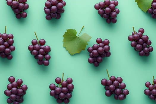 Plump purple grapes and a single green leaf are beautifully arranged on a vibrant green surface, showcasing their freshness and color.