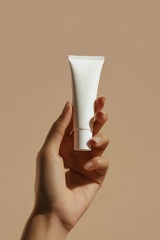 A hand presents a minimalist white tube of cosmetic cream against a soft, neutral background, highlighting skincare products.
