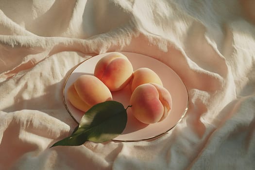 Ripe peaches sit on a delicate plate against a light fabric backdrop, highlighting their natural colors and textures.