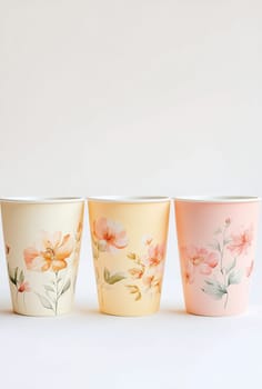 Three beautifully designed paper cups featuring floral patterns in soft colors, perfect for serving drinks at gatherings or parties.