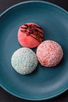 Delicious colorful asian mochi sweets with rice dough shell and fruit filling on dark concrete background