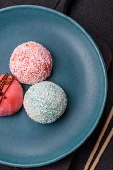 Delicious colorful asian mochi sweets with rice dough shell and fruit filling on dark concrete background