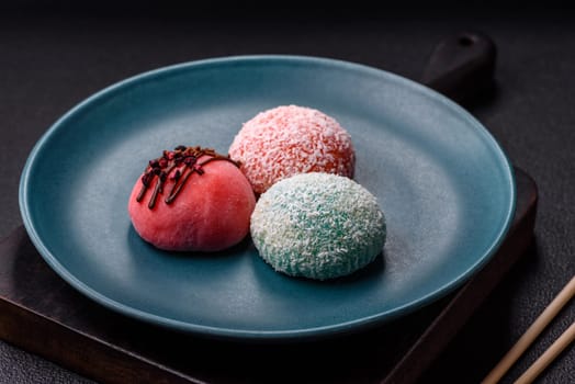 Delicious colorful asian mochi sweets with rice dough shell and fruit filling on dark concrete background