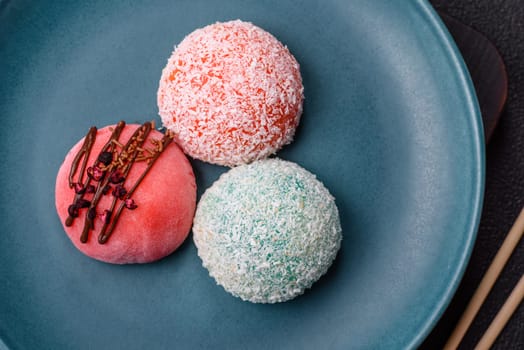 Delicious colorful asian mochi sweets with rice dough shell and fruit filling on dark concrete background