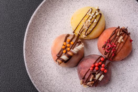 Delicious colorful asian mochi sweets with rice dough shell and fruit filling on dark concrete background