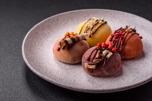 Delicious colorful asian mochi sweets with rice dough shell and fruit filling on dark concrete background