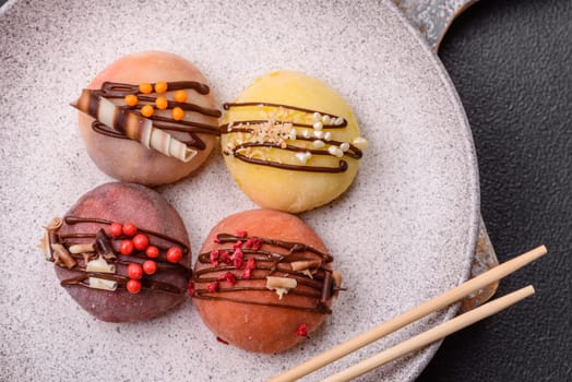 Delicious colorful asian mochi sweets with rice dough shell and fruit filling on dark concrete background