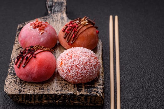 Delicious colorful asian mochi sweets with rice dough shell and fruit filling on dark concrete background