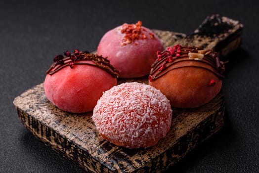 Delicious colorful asian mochi sweets with rice dough shell and fruit filling on dark concrete background