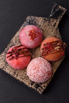 Delicious colorful asian mochi sweets with rice dough shell and fruit filling on dark concrete background