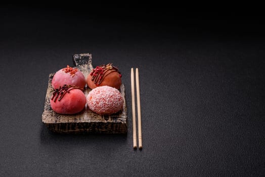 Delicious colorful asian mochi sweets with rice dough shell and fruit filling on dark concrete background