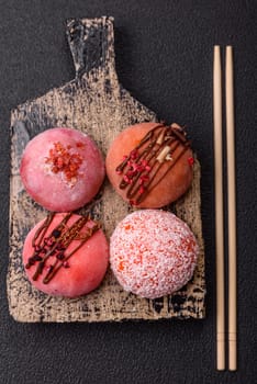 Delicious colorful asian mochi sweets with rice dough shell and fruit filling on dark concrete background