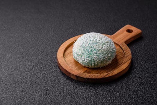 Delicious colorful asian mochi sweets with rice dough shell and fruit filling on dark concrete background