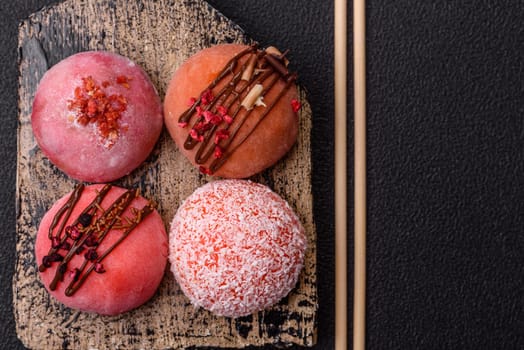 Delicious colorful asian mochi sweets with rice dough shell and fruit filling on dark concrete background