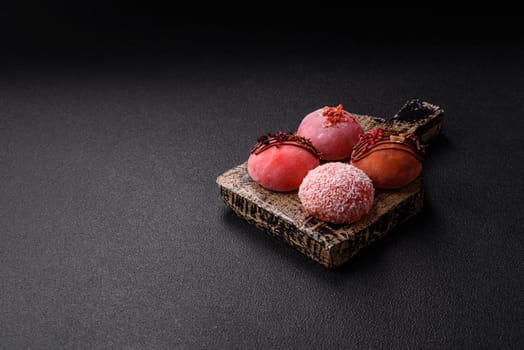 Delicious colorful asian mochi sweets with rice dough shell and fruit filling on dark concrete background