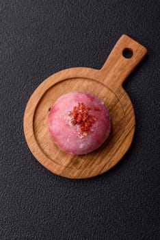 Delicious colorful asian mochi sweets with rice dough shell and fruit filling on dark concrete background