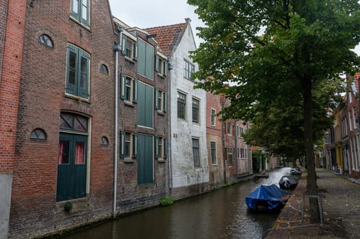Houses on a water canal, a small street and with boats in the old town of Alkmaar in the Netherlands
