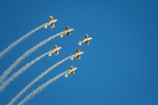 Stunt aerobatic planes in inverted flight performing stunts in blue sky with smoke trail. Concept of teamwork, collaboration, coordination, trust, precision, difficulty, challenge, speed, synergy