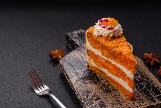 Piece of sweet layer cake with pumpkin or citrus flavor with cream on a dark textured background