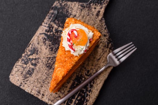 Piece of sweet layer cake with pumpkin or citrus flavor with cream on a dark textured background