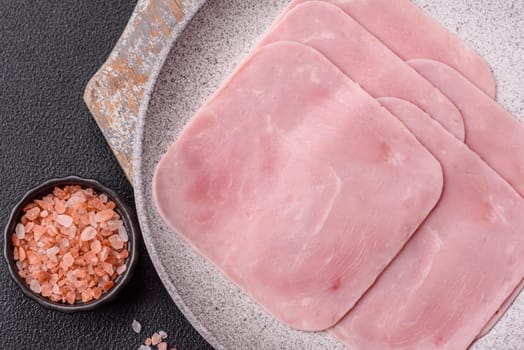 Boiled ham cut into square slices with sorrel and spices on a dark concrete background
