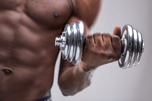 Close-up of a muscular black man lifting a dumbbell, emphasizing dedication to fitness and strength training while highlighting impressive muscle definition and determination