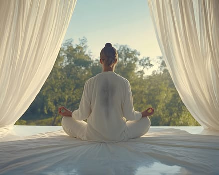 A beautiful young woman is meditating at home, wearing luxurious white clothes. The sunlight is shining down, the fabric is flowing, the beauty is timeless. This image gives a sense of peace.