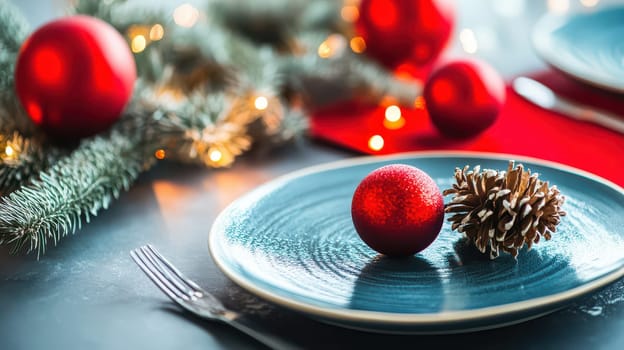 A cozy table setting featuring a blue plate red ornaments and pinecones surrounded by twinkling lights and festive greenery for Christmas.