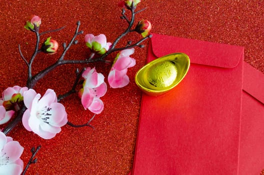 Top view of pink flower, golden ingot and Chinese New Year red packet.