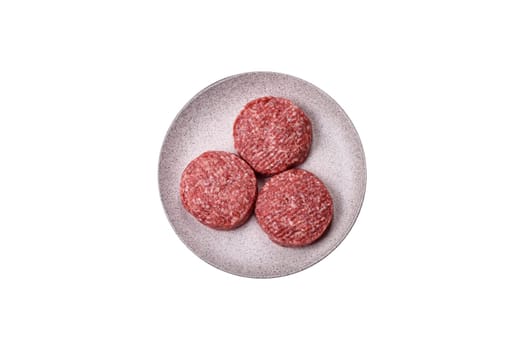 Fresh raw ground beef burger patty with salt and spices on a white background
