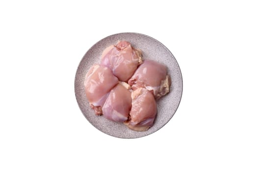 Fresh raw chicken thigh fillets with salt, spices and herbs on a white background